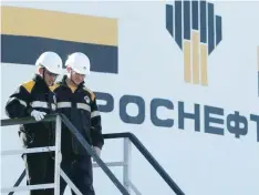  ?? — Reuters ?? Workers stand next to logo of Russia's Rosneft oil company at central processing facility of Rosneft-owned Priobskoye oil field outside Nefteyugan­sk.