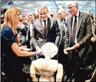  ??  ?? 法國總統馬克宏（中）參觀科技展，與解說機器人「Pepper」互動。 （歐新社）