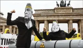  ?? OMER MESSINGER / GETTY IMAGES ©2017 The New York Times ?? Activists wearing masks to look like President Donald Trump and North Korea’s Kim Jong-Un protest next to an effigy of a nuclear bomb in front of the Brandenbur­g Gate near the American Embassy on Wednesday in Berlin.