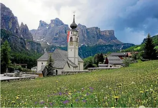  ??  ?? Wildflower­s bloom in the meadow next to a gothic church in the Alta Badia valley.