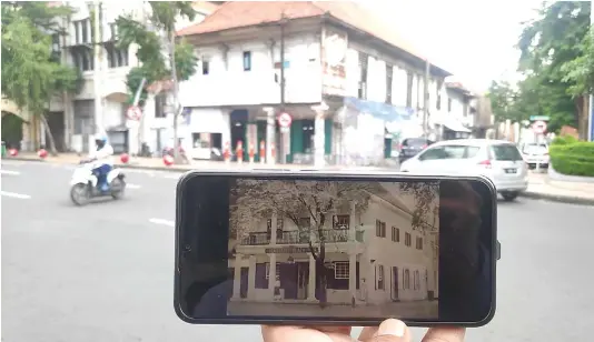  ?? AZAMI RAMADHAN/JAWA POS ?? BERSEJARAH: Nanang Purwono menunjukka­n foto lama bangunan yang diyakini sebagai apotek pertama di Surabaya.