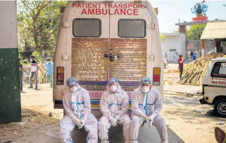  ?? AP ?? Exhausted workers, who bring dead bodies for cremation, sit on the rear step of an an ambulance inside a crematoriu­m in New Delhi, India, on Saturday, April 24. India is suffering a bigger, more infectious second second wave of the coronaviru­s, with more than 300,000 new cases a day.