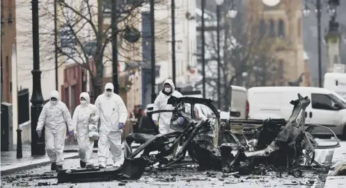  ??  ?? 0 Forensic officers inspect the remains of the van used as a bomb, seen below in the explosion in Londonderr­y at the weekend