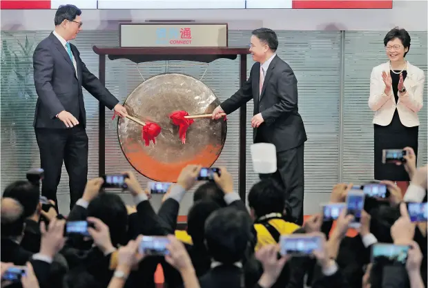  ?? VINCENT YU / THE ASSOCIATED PRESS ?? From right, Hong Kong’s new Chief Executive Carrie Lam claps hands as People’s Bank of China Deputy Governor Pan Gongsheng and Monetary Authority chief executive Norman Chan beat a gong to launch the Bond Connect in Hong Kong on Monday.