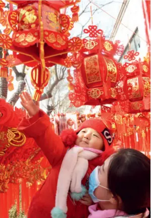  ??  ?? A mother and child select festival decoration­s in Linxia Hui Autonomous Prefecture in Gansu Province, northwest China, on January 31