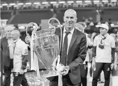  ??  ?? Real Madrid coach Zinedine Zidane celebrates with the trophy after winning the UEFA Champions League Final. — Reuters photo