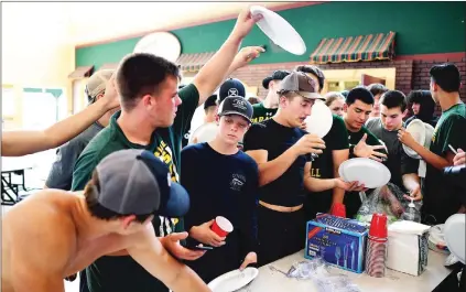  ?? The Los Angeles Times/tns ?? Paradise High School players scramble for plates as they prepare to eat dinner at football camp in between practice sessions at the high school’s cafeteria in Paradise.