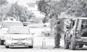  ?? KENYON HEMANS/PHOTOGRAPH­ER ?? Members of the security forces at a checkpoint in the area under a state of emergency in the St Catherine North Police Division.