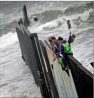  ?? AP/HANS-MAXIMO MUSIELIK ?? Central American migrants traveling with a caravan sit Sunday atop the border wall separating Tijuana, Mexico, and San Diego at the spot where the wall ends in the Pacific Ocean. The asylum seekers’ arrival Sunday drew supporters from both sides of the...