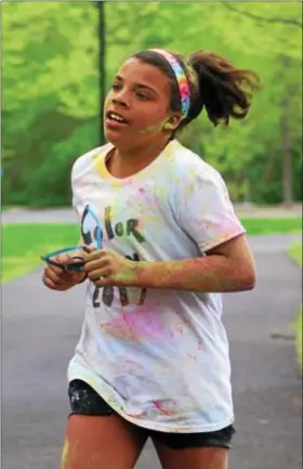  ?? MICHILEA PATTERSON — DIGITAL FIRST MEDIA ?? Bridget Flaherty, 11, runs toward the finish line covered in colored powder during the local YWCA Race Against Racism 5K at Riverfront Park in Pottstown on Saturday. Flaherty was the first girl to finish the race and came in 3rd place overall.