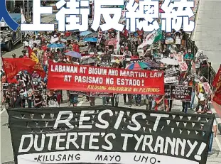  ??  ?? 菲律賓民眾在在前獨裁­者實施戒嚴45週年紀­念日上天反暴政，示威民眾拉布條反抗杜­特爾專制。（歐新社照片）