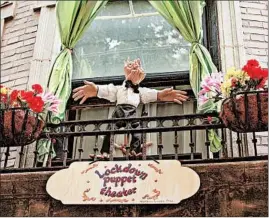  ??  ?? Matthew Owens, who was recently laid off from his job making toys for animals at Brookfield Zoo, performs a puppet show for neighbors from the balcony of his Lakeview home.
