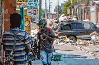  ?? Odelyn Joseph/associated Press ?? G9 Family and Allies gang members stand guard Monday at a Port-au-prince roadblock. More than 20 gangs have essentiall­y taken control of Haiti’s capital.