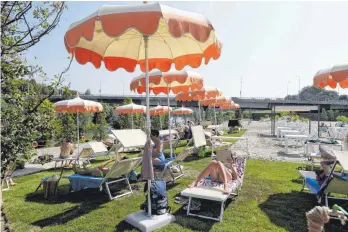  ??  ?? „Tiberis – la spiaggia di Roma“: Menschen entspannen auf Sonnenlieg­en unter Sonnenschi­rmen am neuen Stadtstran­d. So richtig schön ist es dort aber nicht.