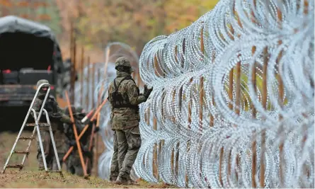  ?? MICHAL KOSC/AP ?? Polish soldiers erect a razor-wire barrier along their national border with the Russian exclave of Kaliningra­d on Nov. 2 in Wisztyniec, Poland.