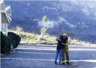  ?? (Photo by Gregory Bull, AP) ?? Firefighte­r Simon Garcia, of Heartland Fire Dept., gets a hug from a woman who did not give her name after she arrived to find her house was intact in the Rancho Monserate Country Club, Friday, Dec. 8, 2017, in Fallbrook, Calif. The wind-swept blazes have forced tens of thousands of evacuation­s and destroyed dozens of homes in Southern California.