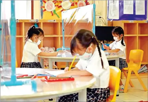  ?? AFP ?? Students attending a class equipped with tables with plastic dividers to prevent the spread of the coronaviru­s at a school in the Thai capital Bangkok.