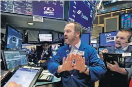  ?? [AP PHOTO] ?? Specialist Charles Boeddingha­us, center, and trader Michael Milano work Wednesday on the floor of the New York Stock Exchange.