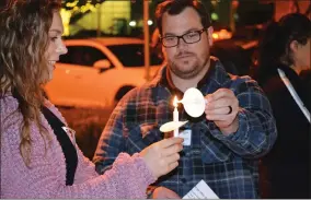  ?? RECORDER PHOTO BY ALEXIS ESPINOZA ?? Candle flames are passed from person to person at the Optimal Hospice Foundation’s ‘Light Up A Life’ event Wednesday evening.