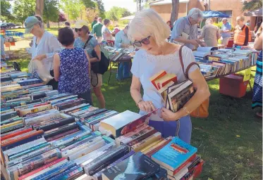  ?? GREG SORBER/JOURNAL ?? Wanda Barrows of Corrales peruses the books at the Friends of Corrales Library Spring Book Sale in La Entrada Park on Sunday. Thousands of books, most priced at $2 for hardback and $1 for paperback, were up for sale, with proceeds supporting the...