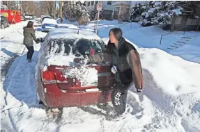  ?? MICHAEL SEARS / MILWAUKEE JOURNAL SENTINEL ?? East side residents Elorine Klockow (left) and Jenai Ellner once again clear off their car in the 3200 block of North Bartlett Avenue on Monday.