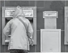  ?? — Reuters photo ?? A customer uses a cash machine at a branch of the Ulster Bank in Coleraine, Northern Ireland.