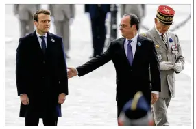 ?? FRANCOIS MORI / POOL / AP ?? French President Francois Hollande (right) reaches out Monday for President-elect Emmanuel Macron during a Victory Day ceremony in Paris.