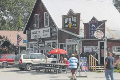  ?? Photos by Mark Thiessen, The Associated Press ?? Tourists walk along historic Main Street in Talkeetna, Alaska. The arrival of the High Expedition Co., the first marijuana store in the town, has caused a divide among residents.