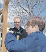  ??  ?? Zavier Bond hammers a nail in a wooden cross as part of this year’s Journey of the Cross.