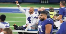  ?? Michael Ainsworth / Associated Press ?? Cowboys quarterbac­k Dak Prescott (4) lifts his fist to cheers from fans as he is carted off the field after suffering a leg injury.