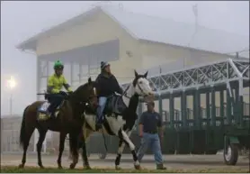  ?? PATRICK SEMANSKY - THE ASSOCIATED PRESS ?? FILE - In this May 15, 2014, file photo, Preakness contender Kid Cruz, left, with exercise rider Reul Munoz aboard, walks past the grandstand after a workout under a thick layer of fog at Pimlico Race Course in Baltimore. The future of Pimlico has turned into a tug of war involving city officials, who want it to stay in Baltimore, and the owners of the track, who long to move the second jewel of the Triple Crown to nearby Laurel.