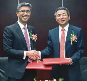  ??  ?? Zafrul (kiri) ketika bertukar dokumen perjanjian China Galaxy Securities, Gu Weiguo, di Beijing. dengan Presiden
