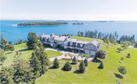  ??  ?? The imposing two-storey house with grey wood siding and white trim stands amid the groomed lawns, lush trees and ponds that comprise the property — navigable by golf carts. The island is a five-minute boat ride from the mainland.