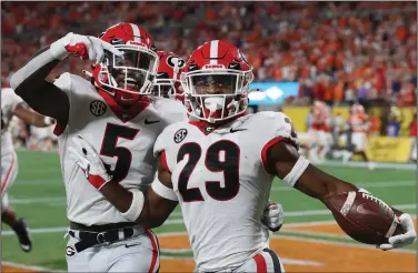  ?? (AP/Atlanta Journal-Constituti­on/Curtis Compton) ?? Georgia defensive back Christophe­r Smith (right) celebrates with teammate Kelee Ringo after returning an intercepti­on for a touchdown Saturday night against Clemson in Charlotte, N.C. The No. 5 Bulldogs defeated the No. 3 Tigers 10-3.