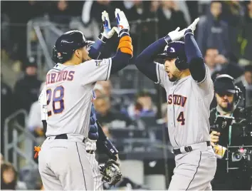  ?? ELSA/GETTY IMAGES ?? The Houston Astros’ George Springer, right, is congratula­ted by teammate Robinson Chirinos after his three-run blast against New York during Game 4 of the ALCS at Yankee Stadium on Thursday.