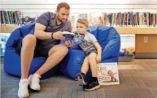  ?? [PHOTOS BY CHRIS LANDSBERGE­R,
THE OKLAHOMAN] ?? LEFT: Alexis Vizarelis reads to his son, Dimitri, 6, in Oklahoma City Public School’s Reading Room at Penn Square Mall.