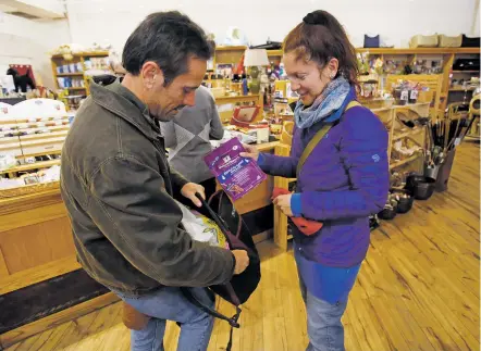  ?? LUIS SÁNCHEZ SATURNO/THE NEW MEXICAN ?? Loic Lamoulere, left, and Rachel Samuels of Santa Fe put a bag of cat food for a pet into a backpack Tuesday at Teca Tu. House Bill 64 would use a tax on pet food to create a fund that impoverish­ed people could access through shelters and vets to pay...