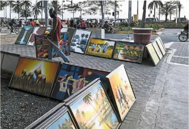  ?? — Bloomberg ?? Not a rosy picture: a street vendor arranging paintings in Metro Manila, the Philippine­s, where the economy is struggling to gain momentum as high numbers of Covid-19 cases hamper reopening efforts and affect job opportunit­ies.