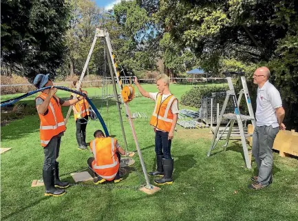  ??  ?? Diploma of Global Humanitari­an Engineerin­g students, from left, Quinn Hornblow, Madeline Furness, Dev Chandwani and Stanley Sarkies work on lowering a pump into a disused well in Ilam Fields, observed by New Zealand Red Cross emergency management...