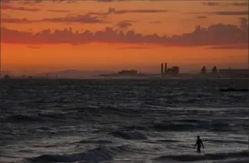  ?? Jae. C. Hong/Associated Press ?? A man wades into the ocean at sunset last June in Newport Beach, Calif. The National Oceanic and Atmospheri­c Administra­tion announced Friday the amount of carbon dioxide in the atmosphere in May averaged 421 parts per million, more than 50% higher than pre-industrial levels.