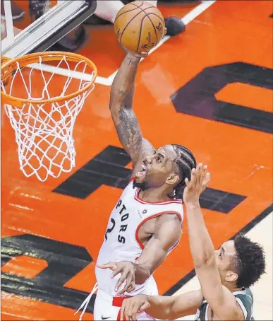  ?? Frank Gunn The Associated Press ?? Toronto forward Kawhi Leonard, left, beating Milwaukee point guard Malcolm Brogdon for a basket, scored 36 points, including eight in the second overtime, in a 118-112 victory Sunday, the Raptors’ first in the Eastern Conference final.