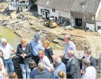  ?? AP ?? German Chancellor Angela Merkel, rear second left, folds her hands as she and the Governor of the German state of Rhineland-Palatinate, Malu Dreyer, rear third right, are seen on a bridge in Schuld, western Germany, Sunday, July 18 during their visit in the flood-ravaged areas to survey the damage and meet survivors.