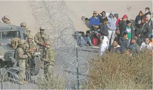  ?? CHRISTIAN CHAVEZ/ASSOCIATED PRESS ?? The Texas National Guard stop migrants from crossing Tuesday into El Paso from Ciudad Juárez, Mexico. Texas Gov. Greg Abbott sent more than 500 soldiers to the border region.