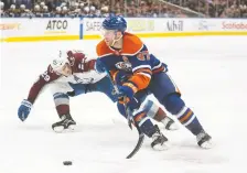  ?? JASON FRANSON/ THE CANADIAN PRESS ?? Colorado Avalanche's Nathan Mackinnon, left, and the Oilers' Connor Mcdavid battle for the puck during overtime of their game Saturday night in Edmonton. The Avs won 3-2.