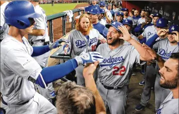  ?? LOS ANGELES TIMES ?? The Dodgers’ Cody Bellinger (left) is congratula­ted by teammates in the fifth inning Monday after his solo home run against Arizona. Game 3 of the NLDS at Chase Field ended with an L.A. win and a series sweep.