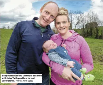  ?? Photo: John Delea ?? Briege and husband Diarmuid Scannell with baby Tadhg on their farm at Crookstown.