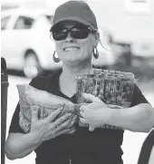  ??  ?? Volunteer Carol Taylor readies some fresh produce for distributi­on to those who need it.