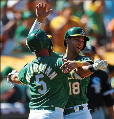  ?? JASON O. WATSON — GETTY IMAGES ?? Chad Pinder, right, is congratula­ted by Chris Herrmann after scoring the A’s winning run against the White Sox on Sunday.
