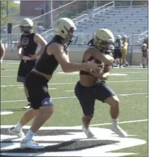  ?? ALEX FARRER / staff ?? Calhoun quarterbac­k Baylon Spector (left) hands off to Olico Dennis during a drill on Monday. For more photos from Monday’s Calhoun and GC practices, see