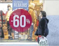  ?? EUROPA PRESS ?? Una mujer pasa frente a un cartel que anuncia rebajas.